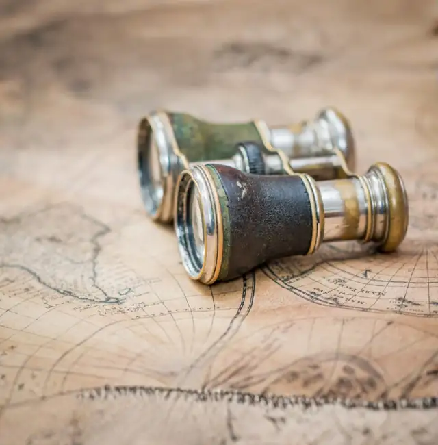 Vintage binoculars resting on a world map