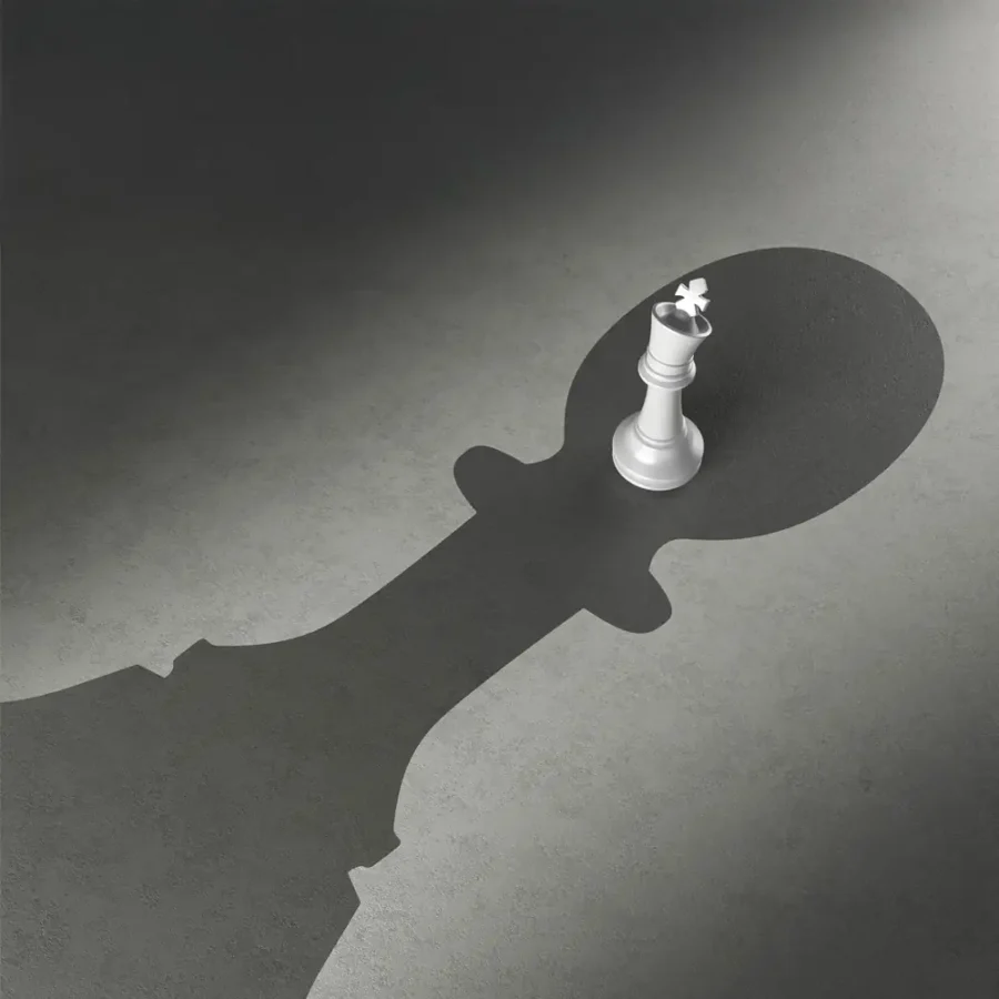 White chess piece casting a large king-shaped shadow on a grey surface